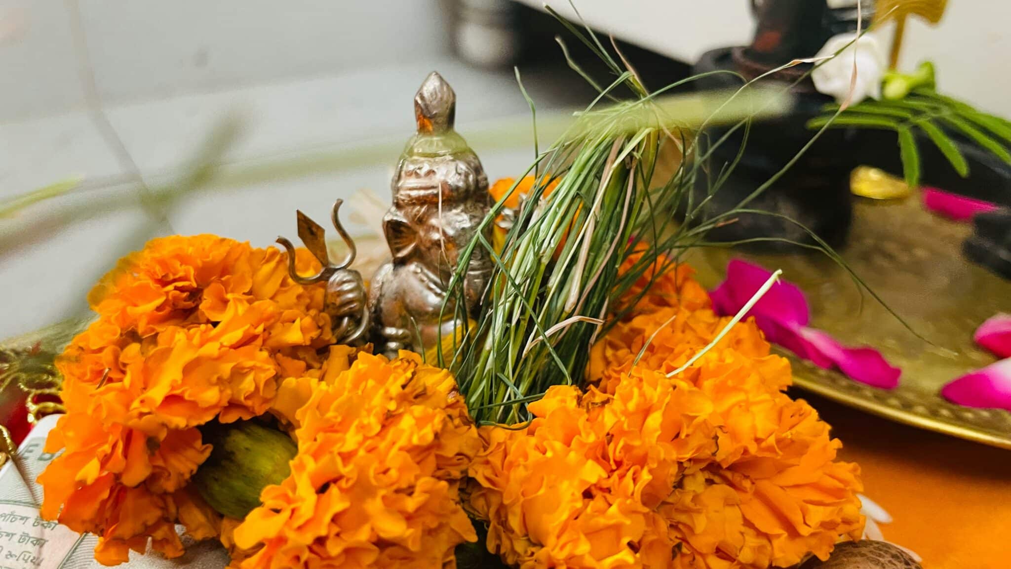 Flowers on top of the table surrounding the little statue of Ganesh